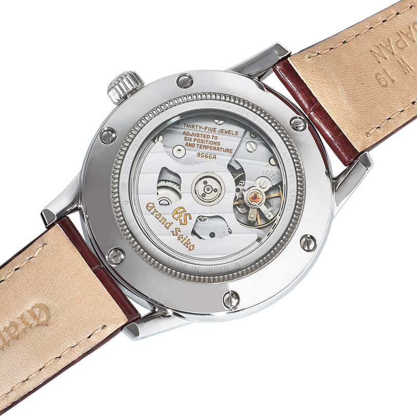 Back view of the Grand Seiko Automatic GMT Elegance showcases its automatic movement through a transparent case back, set in stainless steel with tan leather straps—an elegant timepiece exemplifying Grand Seiko precision.