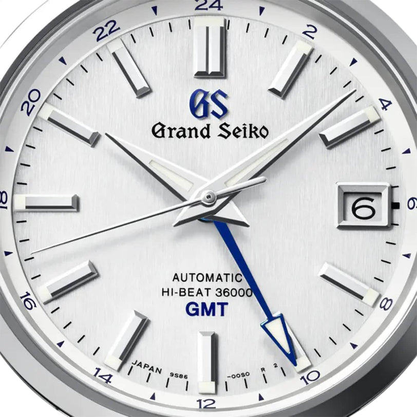 Close-up of the Grand Seiko Hi-Beat GMT Heritage watch face at 7:52:31, featuring a blue GMT hand, date window at 3 oclock, silver hour markers on white—powered by the impressive 9S86 Hi-Beat 36,000 Mechanical movement.