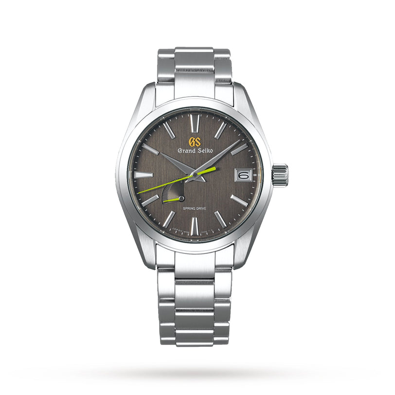 The Grand Seiko Spring Drive Heritage is a stainless steel wristwatch with Japanese craftsmanship, a grey textured dial, yellow second hand, date window at 3 o’clock, and silver bracelet, shown on a white background.