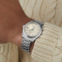 A Grand Seiko Hi-Beat Heritage wristwatch with a cream dial and date display, elegantly worn on the wrist, pairs perfectly with a cream cable-knit sweater.