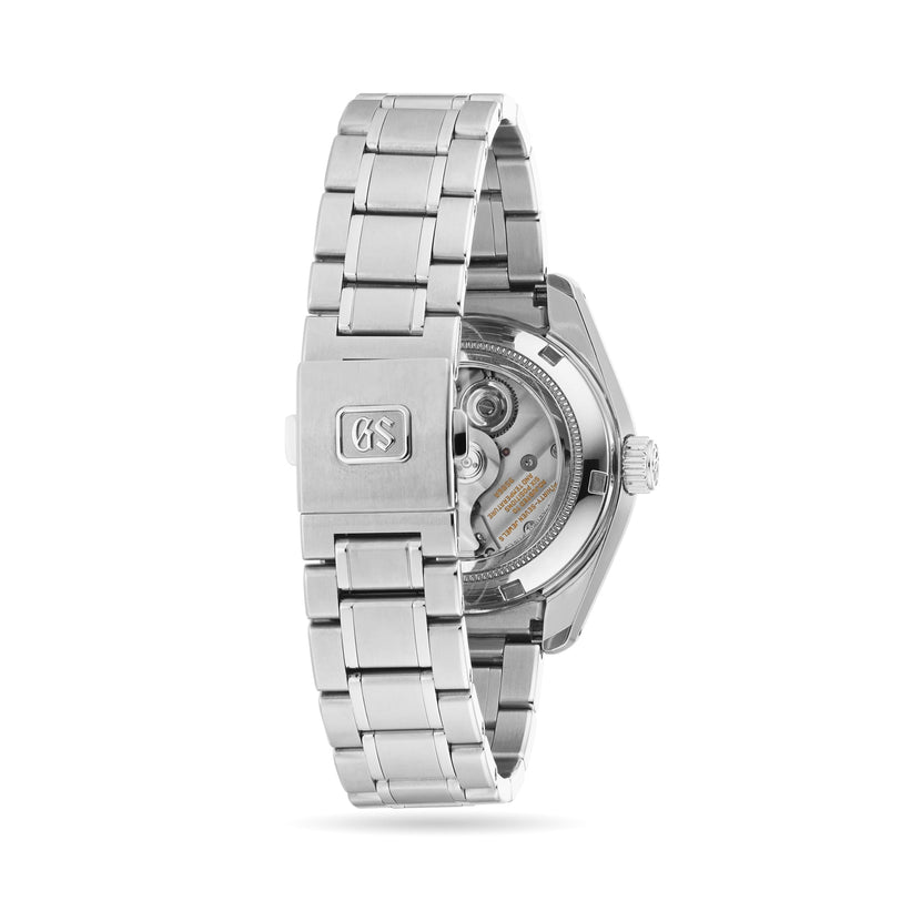 A close-up of the stainless steel bracelet and caseback of the Grand Seiko Hi-Beat GMT Heritage watch, featuring the GS logo clasp and a view of its automatic movement through the sapphire caseback.