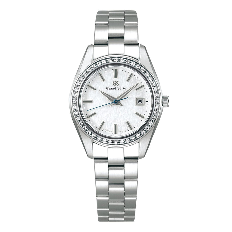 The Grand Seiko Ladies Heritage features a silver stainless steel bracelet, 44 diamonds on the bezel, a snowflake dial with date at 3 o’clock, blued steel seconds hand, and simple index hour markers.