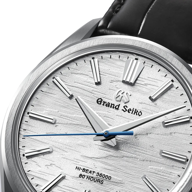 Close-up of the Grand Seiko Manual Hi-beat 80 Hours Evolution 9, featuring a white birch bark-textured dial, silver hour markers, blue second hand, and black leather strap—celebrating its 10-beat manual-winding movement.