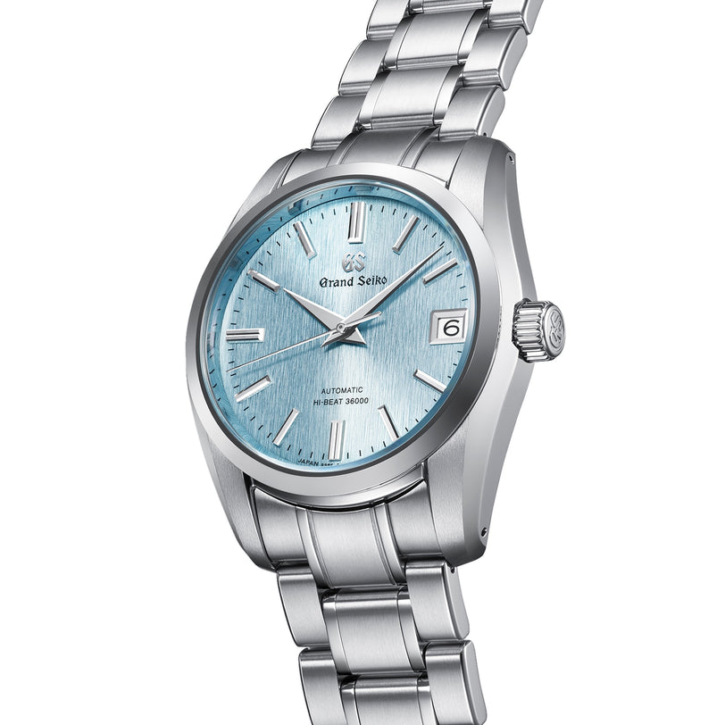 The Grand Seiko Hi-Beat Heritage wristwatch, made from Ever-Brilliant Steel, has a light blue textured dial with silver markers, a date at 3 o’clock, and runs on the precise Hi-Beat Caliber 9S85 movement.