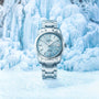 The Grand Seiko Hi-Beat Heritage watch in silver is showcased against a backdrop of blue and white ice formations.