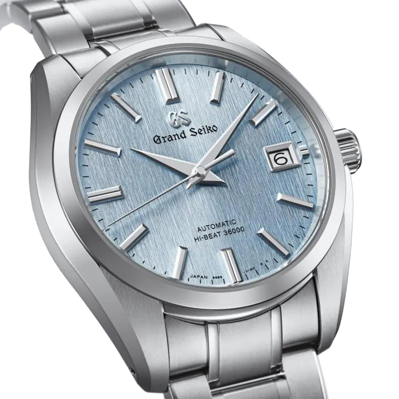 The Grand Seiko Hi-Beat Heritage is a stainless steel watch with a light blue textured dial, silver markers, date at 3 o’clock, and boasts precise Japanese automatic movement.