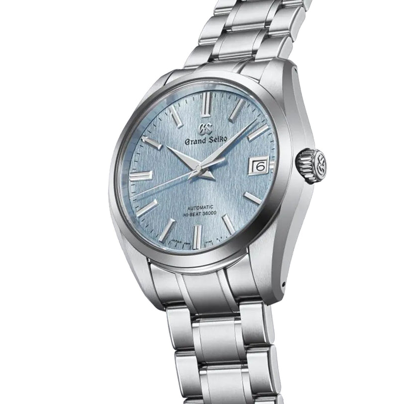 The Grand Seiko Hi-Beat Heritage features a blue textured dial, date at 3 o’clock, and a stainless steel bracelet—showcasing the brand’s mechanical expertise—elegantly displayed on a white background.