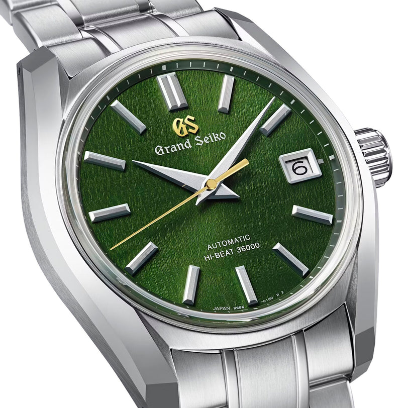 The Grand Seiko Hi-Beat Heritage wristwatch features a deep green dial with silver markers and hands, date window at 3 o’clock, Hi-Beat Caliber 9S85 movement, and a Zaratsu-polished stainless steel bracelet.