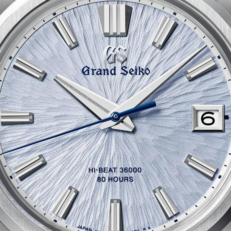 Close-up of the Grand Seiko Hi-Beat 80 Hours Evolution 9 watch, featuring a textured silver dial inspired by mountains, blue second hand, date window at 3 o’clock, and “HI-BEAT 36000 80 HOURS” text—honoring Grand Seiko’s 65th Anniversary.