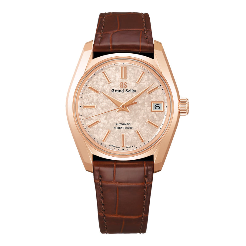 The Grand Seiko Hi-Beat Heritage is a rose gold mechanical watch with a textured cream dial, sakura-kakushi motif, date window at 3 o’clock, and a brown leather strap.