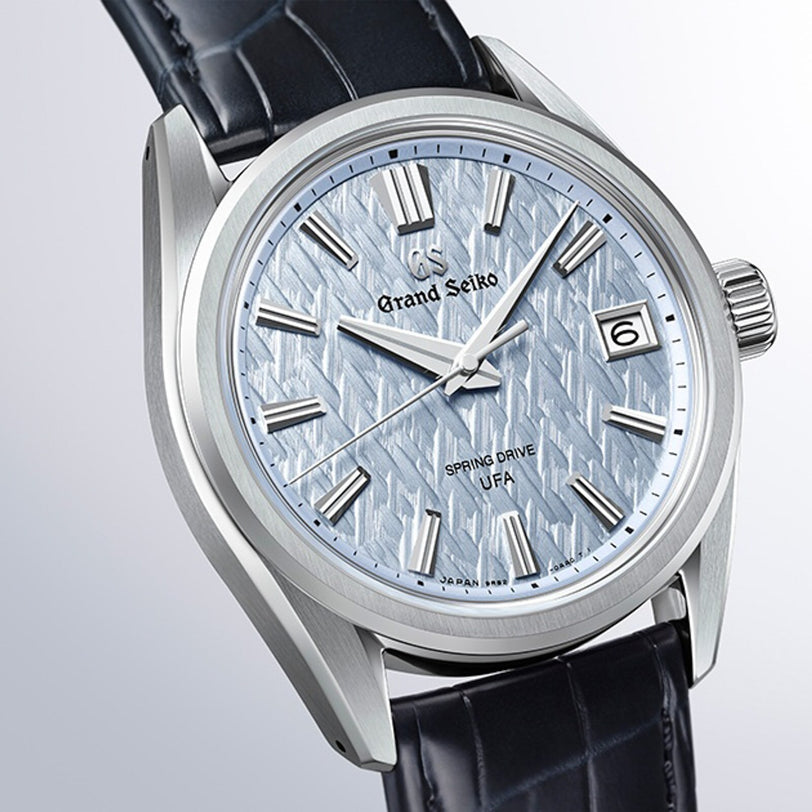 Close-up of the Grand Seiko Spring Drive U.F.A Evolution 9 wristwatch featuring a textured light blue dial and black leather strap.