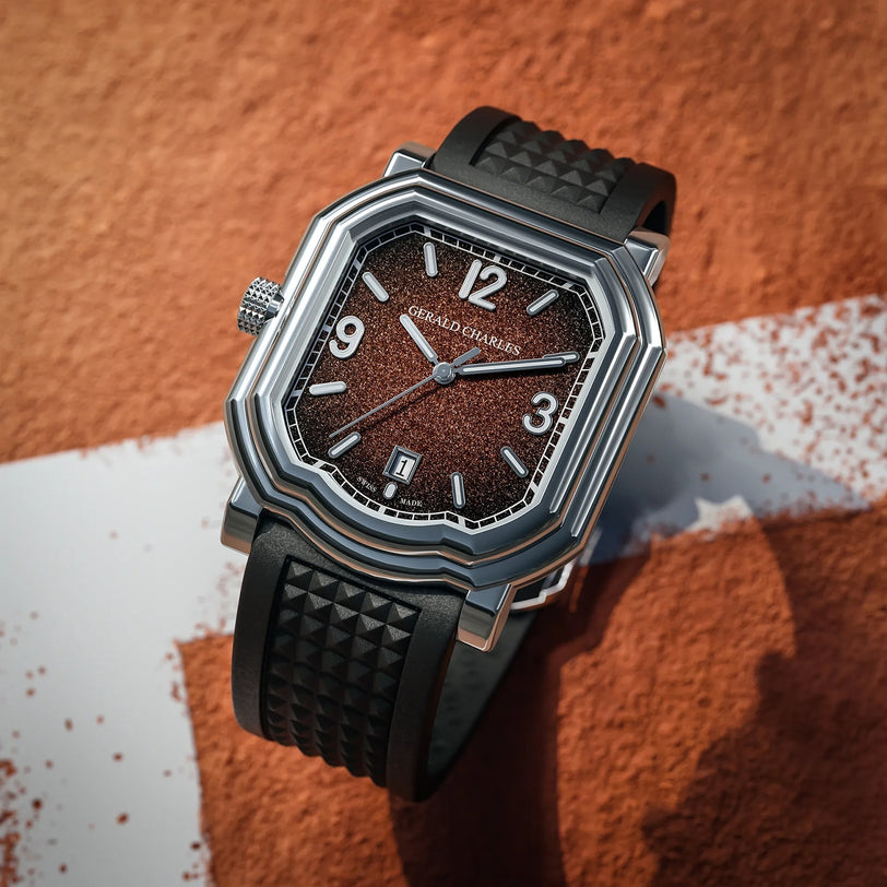 The Gerald Charles Maestro GC Sport luxury watch, featuring a textured brown face and black strap, rests on a brown and white surface.