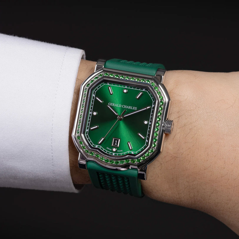 A person wears the Gerald Charles Maestro 2.0 Ultra-Thin Gem-Set, featuring an emerald green sunburst dial, a gem-set bezel adorned with precious stones, and a matching vulcanised rubber strap.