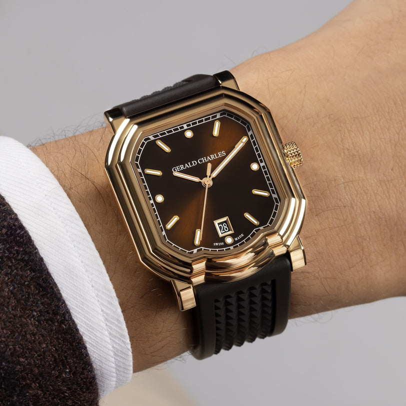 A Gerald Charles Maestro 2.0 Ultra-Thin gold wristwatch with a black strap is shown on a persons wrist, displaying the time 10:10.