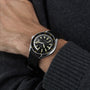 A person wearing a DOXA Sub 200 Sharkhunter with a 316L stainless steel mesh strap on their left wrist, dressed in a dark knit sweater.
