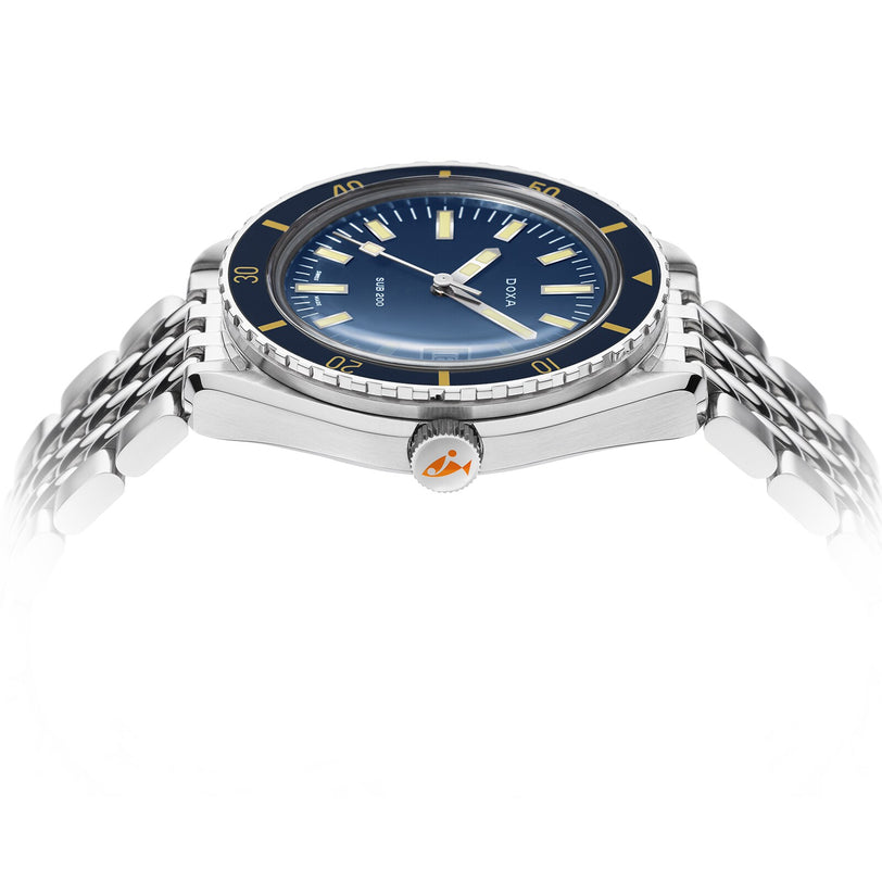 The DOXA Sub 200 Caribbean, a 316L stainless steel diver’s watch with a blue dial, yellow markers, and silver link bracelet, is shot from a low side angle to highlight its unidirectional rotating bezel.