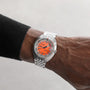 A person wearing a DOXA Sub 300 Professional silver divers watch with an orange dial and metal bracelet, shown close-up against a neutral background.