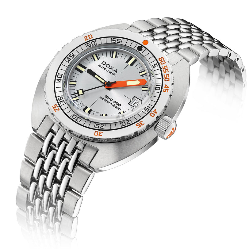 A DOXA Sub 300 Searambler diver’s watch with a white dial, orange accents, unidirectional bezel, and stainless steel bracelet is displayed on a white background.