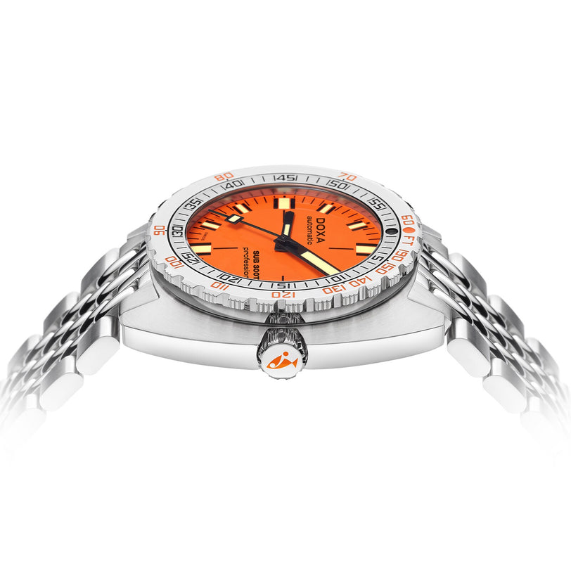 A DOXA Sub 300T Professional divers watch, featuring a stainless steel case, orange dial, black and white hands, silver bezel with red accents, metal bracelet, and helium release valve, shown from a low angle.