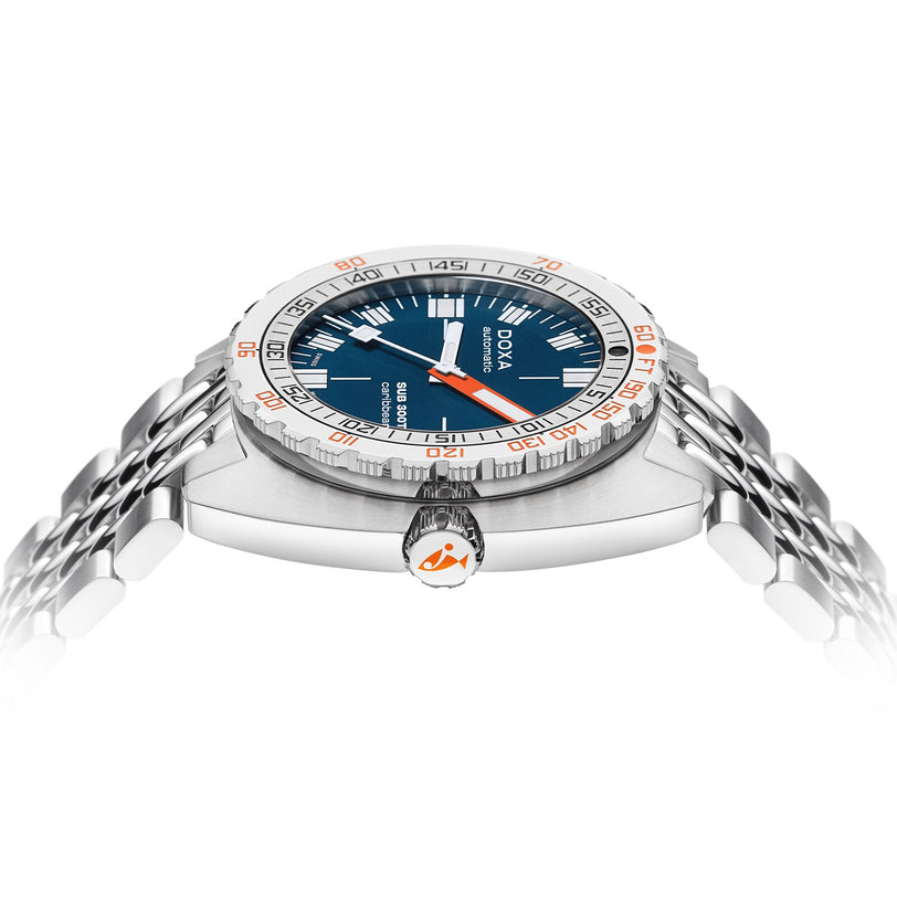 The DOXA Sub 300T Caribbean is a stainless steel divers watch with a blue dial, silver and orange minute markings, and a metal bracelet, shown from a low side angle.