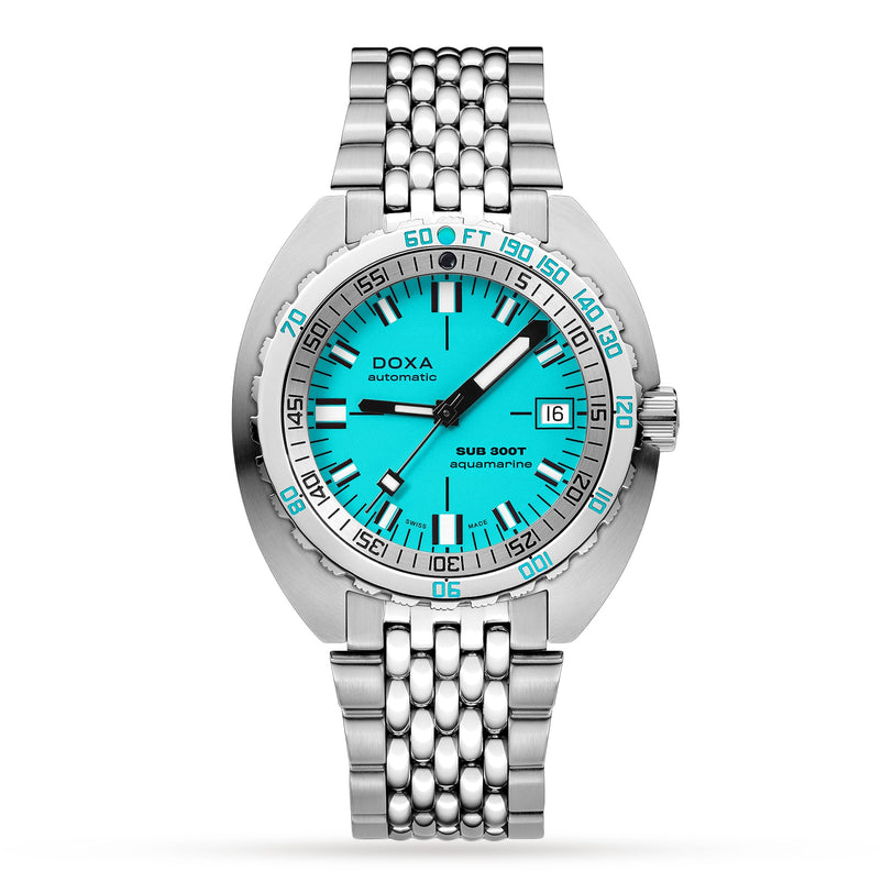 The DOXA Sub 300T Aquamarine is a stainless steel diver’s watch with an aquamarine dial, date at 3 o’clock, helium release valve, metal link bracelet, and a bezel showing depth in feet and meters.