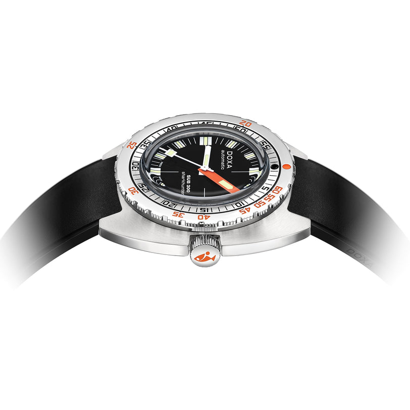 The DOXA Sub 300 Sharkhunter diver’s watch, shown at an angle, features a silver case, black dial with orange accents, a black rubber strap, and vibrant orange details on the unidirectional bezel and crown.