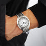 Someone wearing the DOXA Sub 300T Whitepearl, a silver wristwatch with a white dial and metal band, has their hand in their jacket pocket.