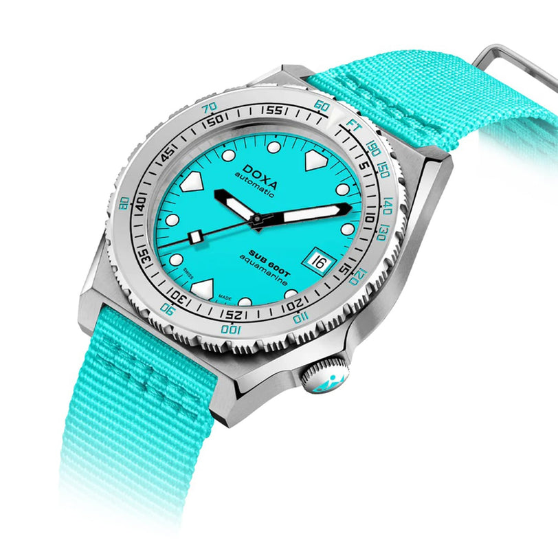 The DOXA Sub 600T Aquamarine features a stainless steel case, aquamarine dial, matching fabric strap, date display at 3 o’clock, and a silver bezel with black markings.