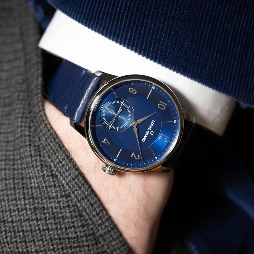 Close-up of a wrist wearing the Louis Erard Petite Seconde Bleu Nuit watch with silver details, paired with a suit.