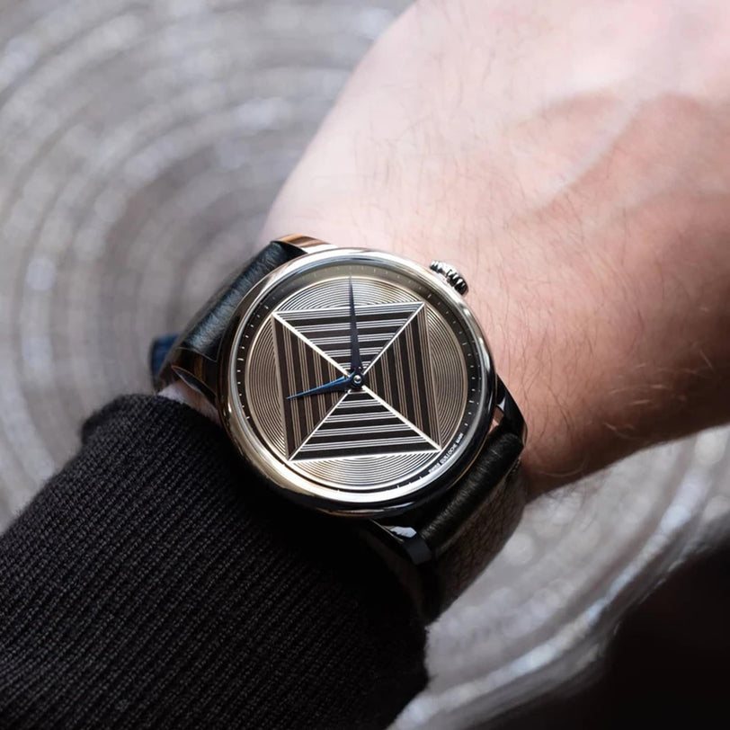 The Louis Erard Guilloché Main II features a geometric striped dial with a star pattern, shown worn on the left wrist.