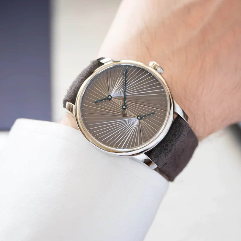 The Louis Erard Le Régulateur Louis Erard x atelier oï is a wristwatch with a radial patterned face and no numbers, shown worn on a person’s left wrist.