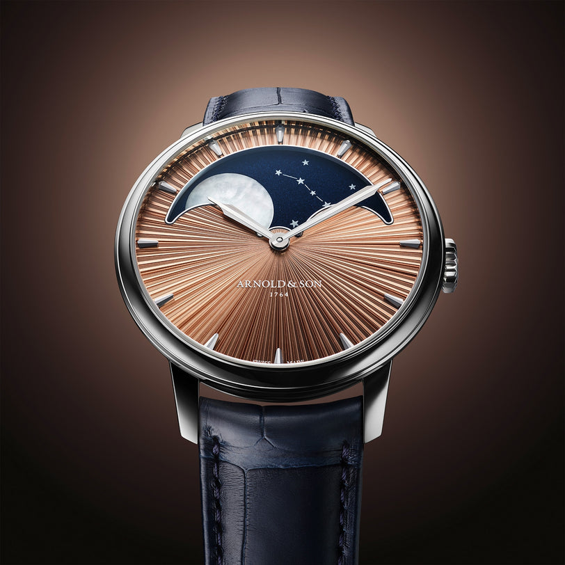 The Arnold & Son Perpetual Moon 41.5mm Platinum is a luxury watch featuring a moonphase dial, elegant sunburst pattern, and a blue leather strap.