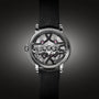 The Arnold & Son Nebula 38 Steel features visible gears and jewels in a skeleton design, a black leather strap, and a metallic case, showcased against a dark background.