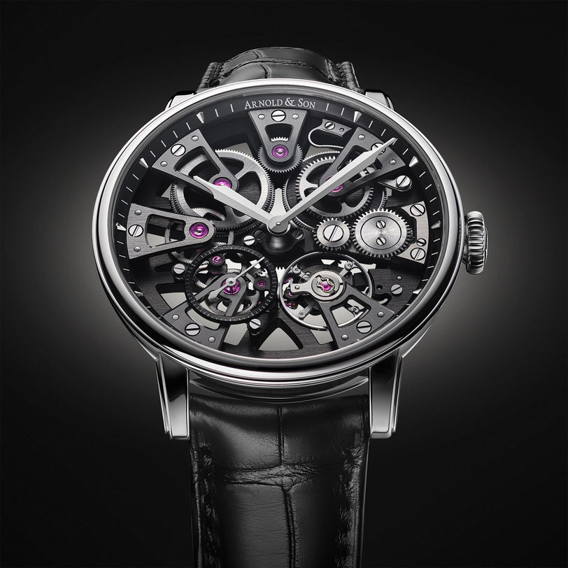 The Arnold & Son Nebula 38 Steel is a luxury skeleton watch with exposed gears and a black leather strap, set against a dark background.