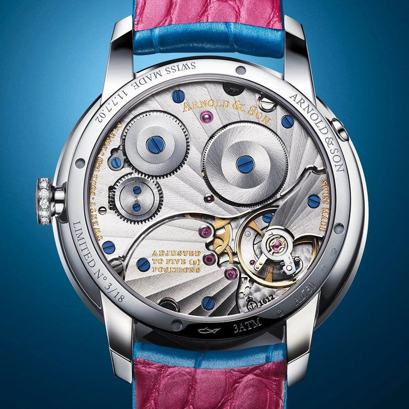 Close-up of the Arnold & Son Perpetual Moon 38 White Gold Mintnight watch back, showcasing intricate gears, engravings, and a blue and pink leather strap.