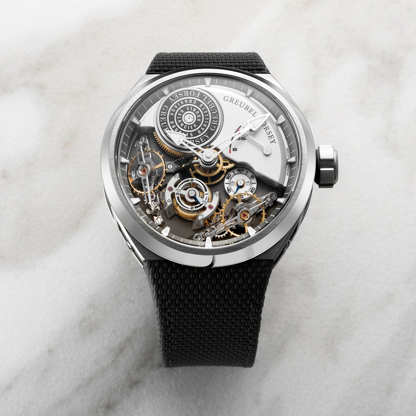 The Greubel Forsey Double Balancier Convexe is a luxury skeleton watch with a black strap, featuring visible gears and intricate inner mechanisms.