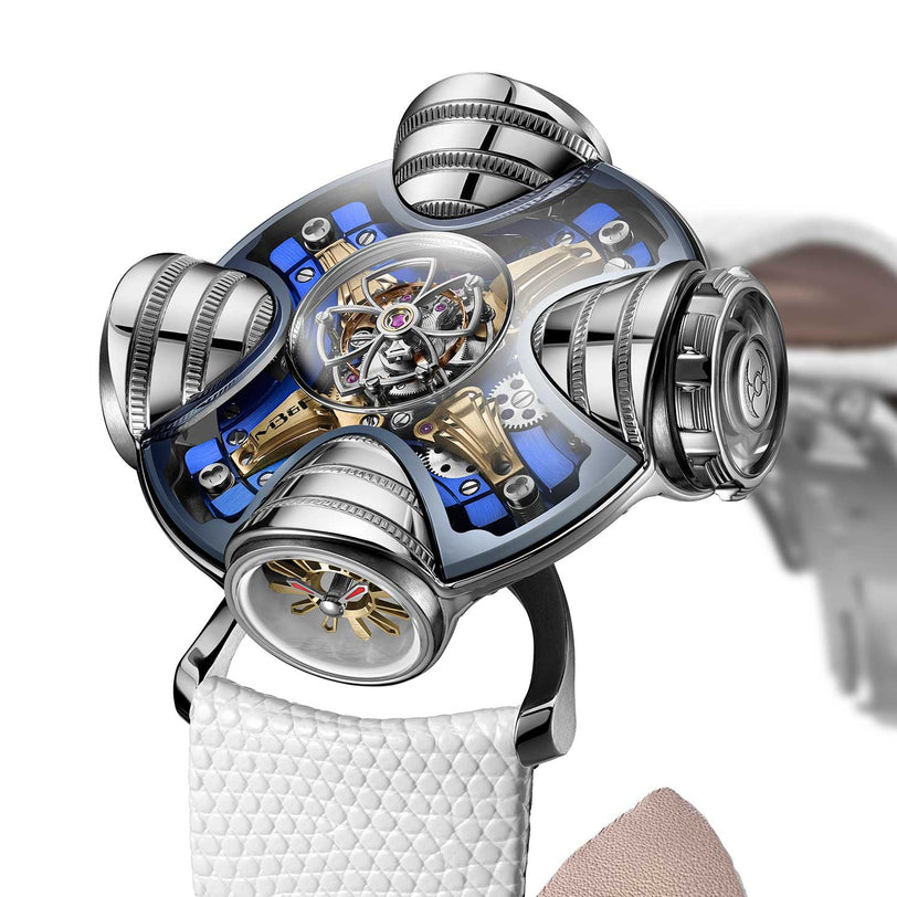The MB&F HM11 Art Deco is a futuristic luxury watch featuring a metallic mechanical design, skeletonised dial with four rounded structures, exposed gears, and a white textured strap.
