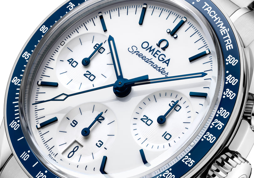Stainless steel chronograph watch with white dial, blue hands and markers, and blue tachymeter bezel.