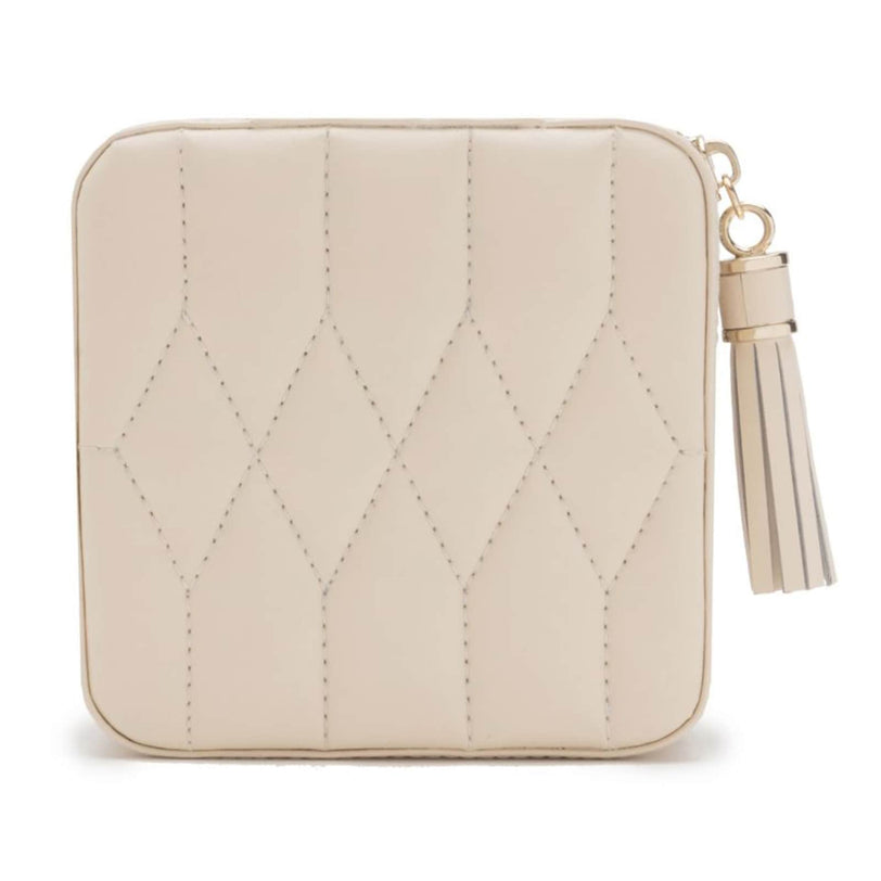 The WOLF Caroline Zip Travel Case is a beige, quilted square pouch featuring a zipper closure and a tassel keychain on the side.