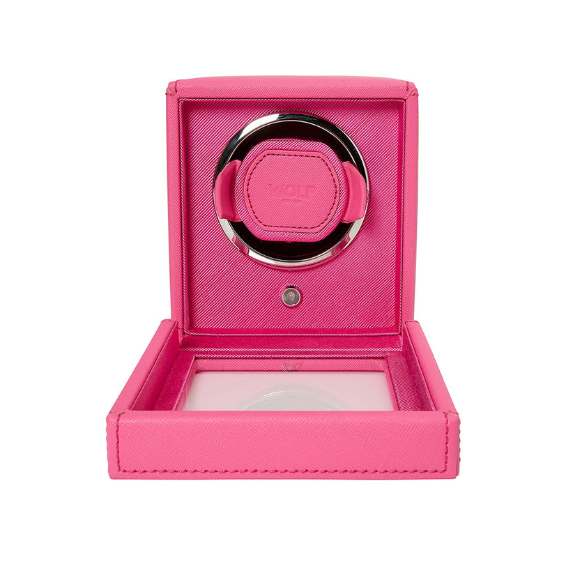 The WOLF Cub Single Watch Winder with Cover is shown open, revealing its circular holder inside. The bright pink finish adds a stylish touch to this elegant watch accessory.