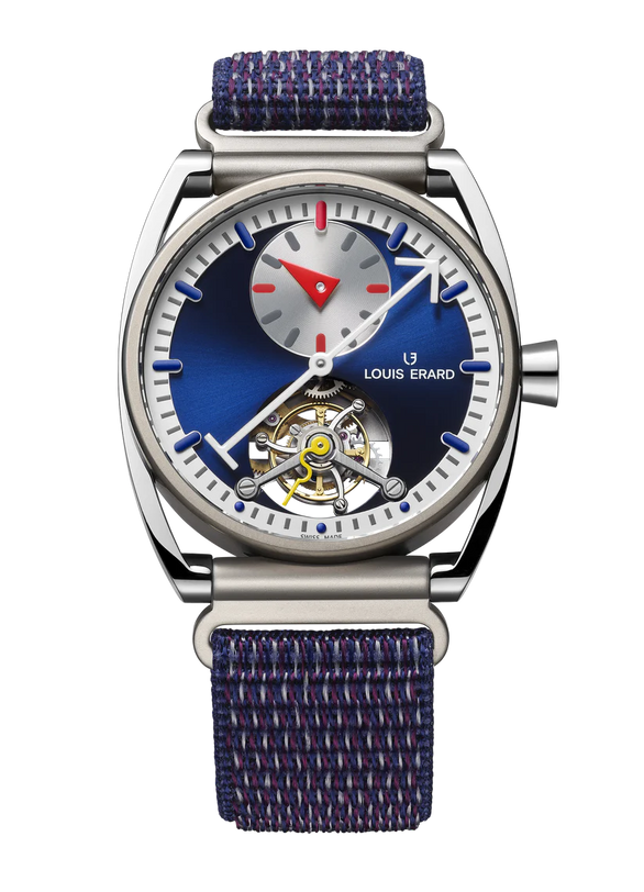 Steel watch with blue dial, visible tourbillon mechanism, small subdial, red triangle hour hand, and blue textile strap.
