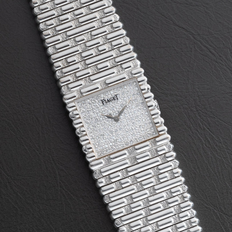 A Piaget Emperador Diamond wristwatch with a textured square dial and matching silver bracelet displayed on a black surface.