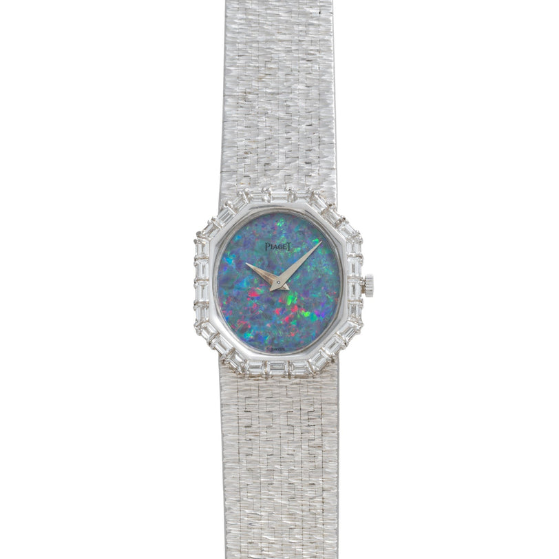 The Piaget Opal White Gold Dress Watch features a textured band, blue opal face, and diamond accents around the bezel.