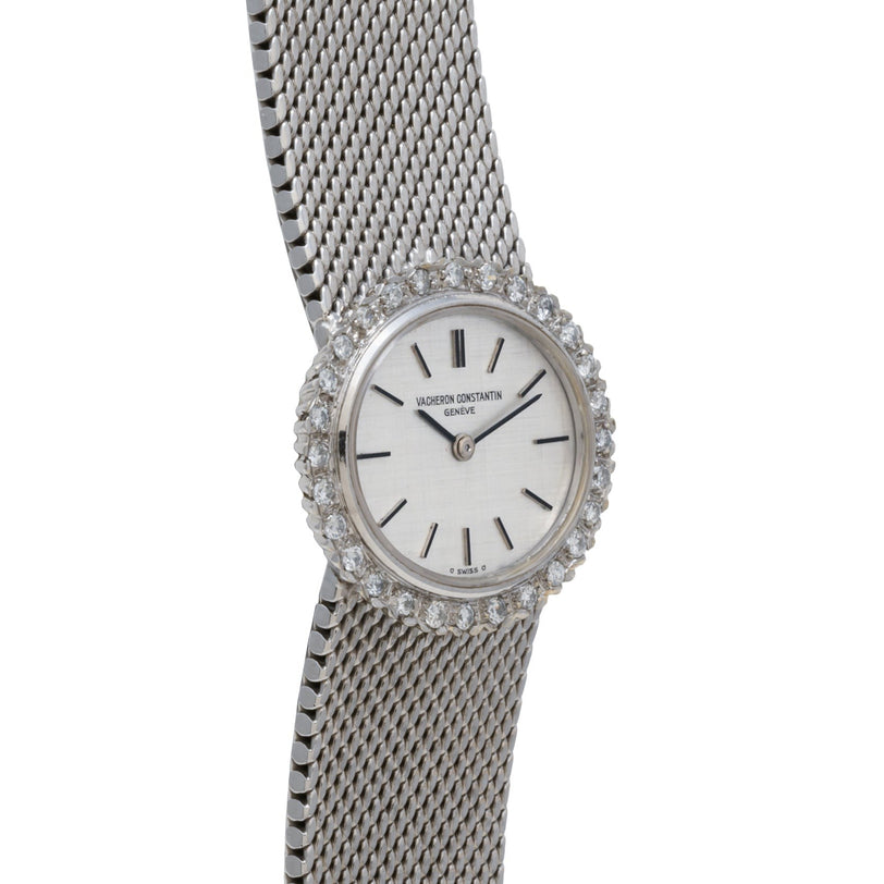 The Vacheron Constantin White Gold Diamond Bezel wristwatch features a silver mesh band, diamond-encrusted bezel, and a minimalist white dial with black hour markers.
