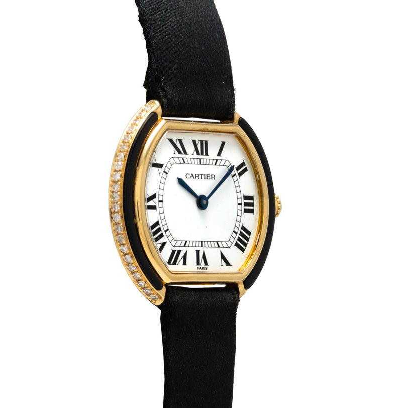 Cartier Ellipse Gondole watch with gold tonneau case, diamond-set bezel, white dial, Roman numerals, and black fabric strap.