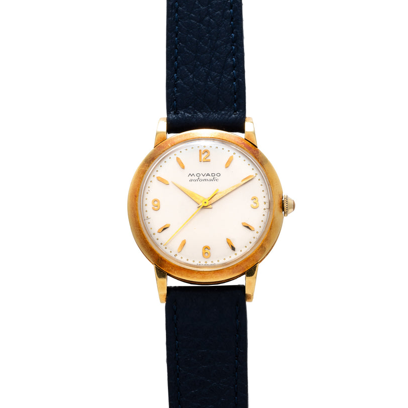 Movado automatic watch with yellow gold round case, white dial, gold numerals and hands, dark blue leather strap.