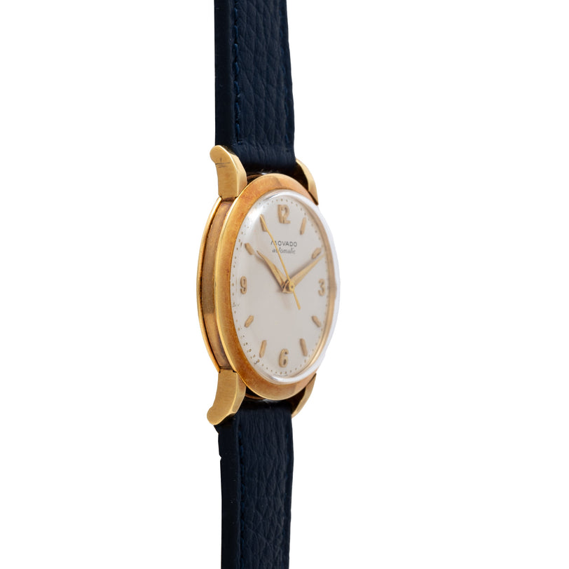 Yellow gold watch with cream dial, gold numerals, and black leather strap.