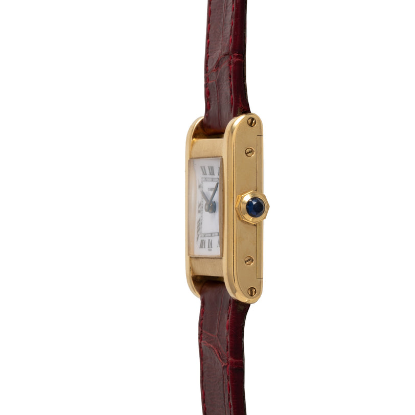Rectangular gold-toned watch with white dial, Roman numerals, blue sapphire crown, and burgundy leather strap.