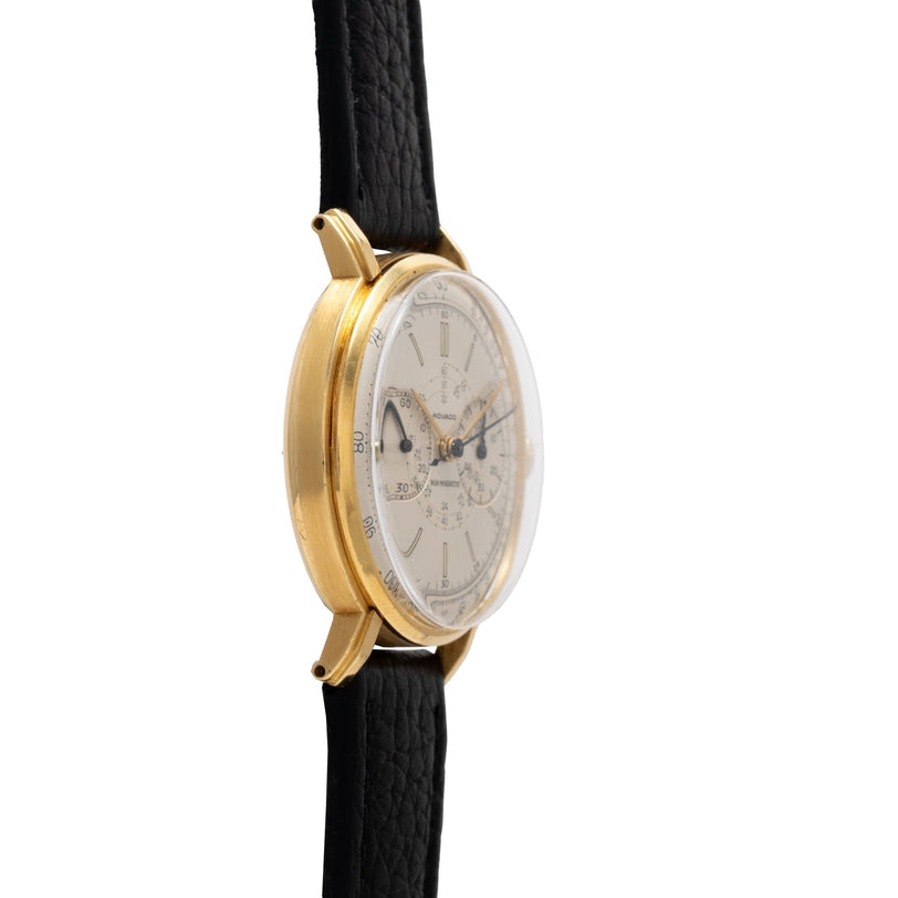 Gold-tone chronograph watch with cream dial, subdials, and black textured leather strap.