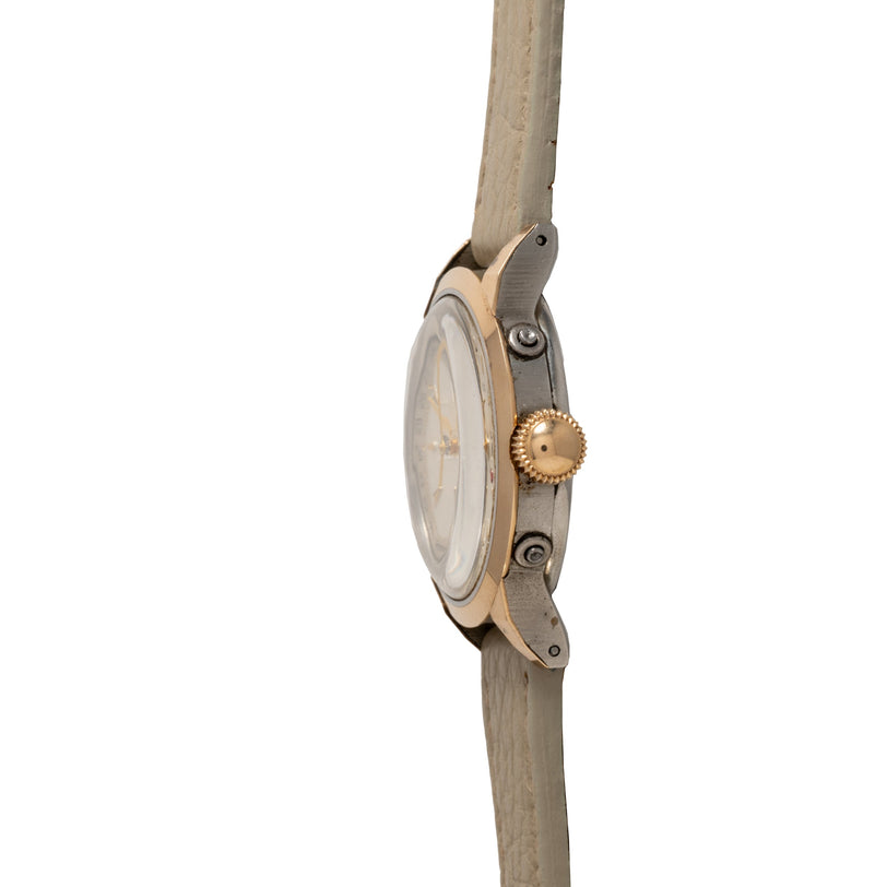 Two-tone Movado watch with gold crown and gray leather strap, displayed on wooden rod at side angle.